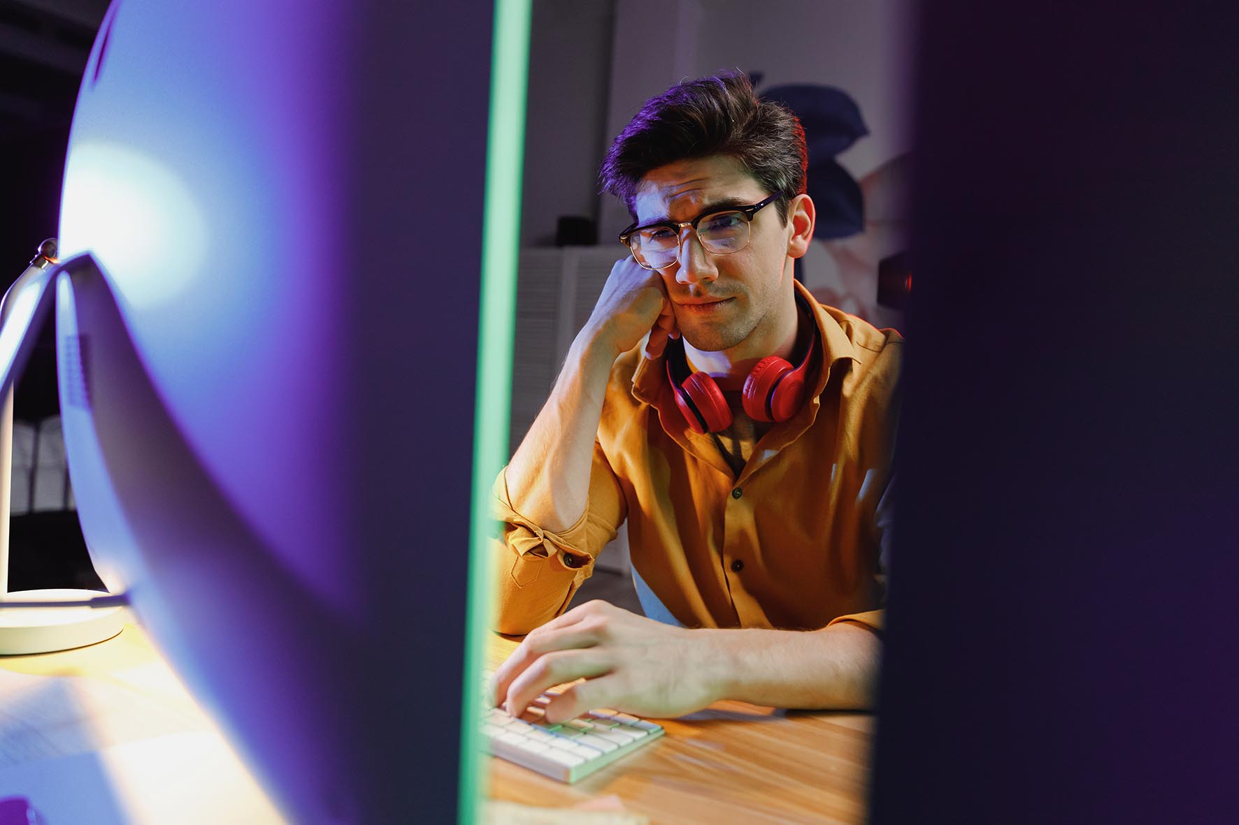 Young man at desk looking at screen, tired