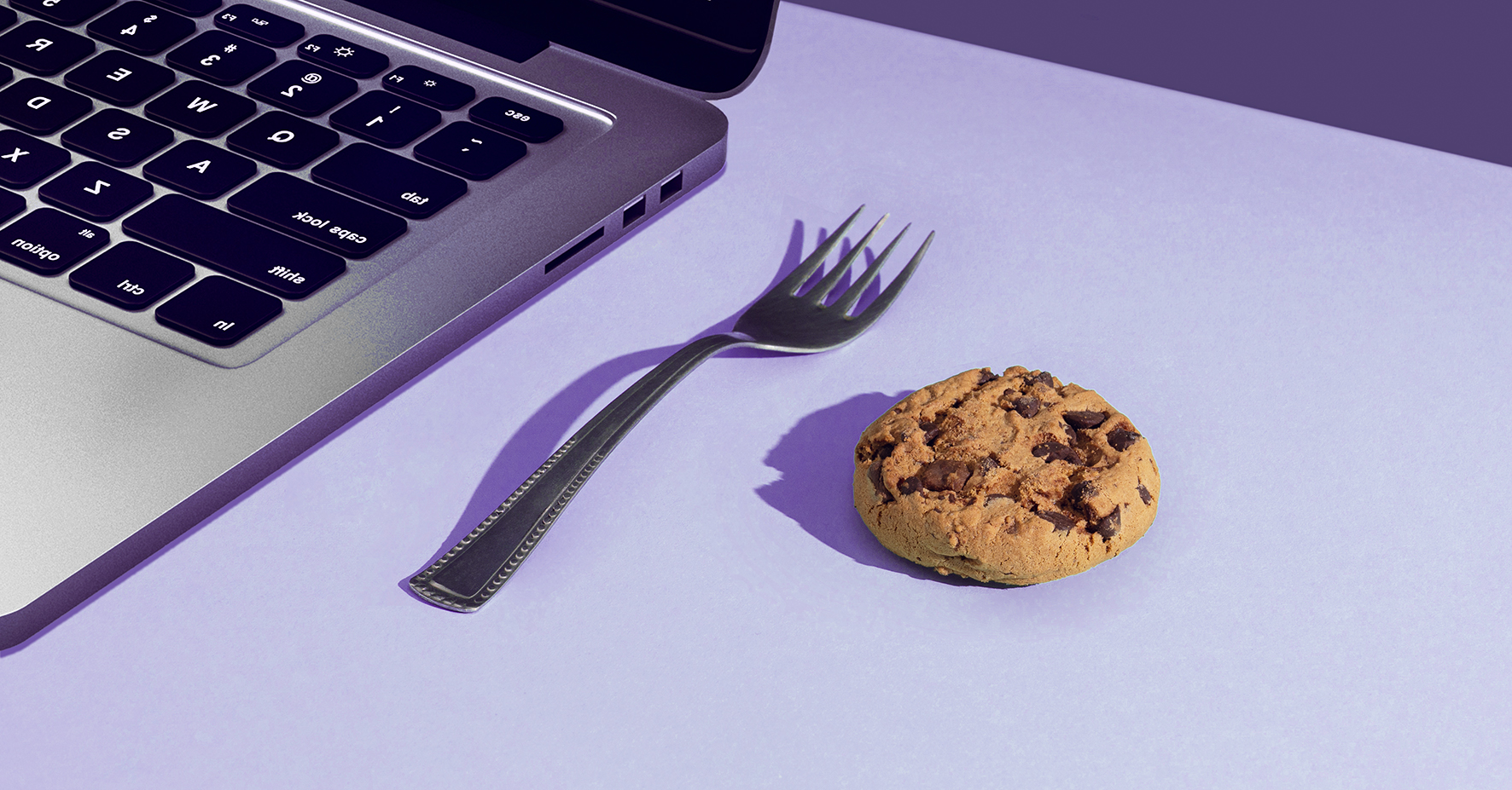 Cookie next to a fork next to a laptop
