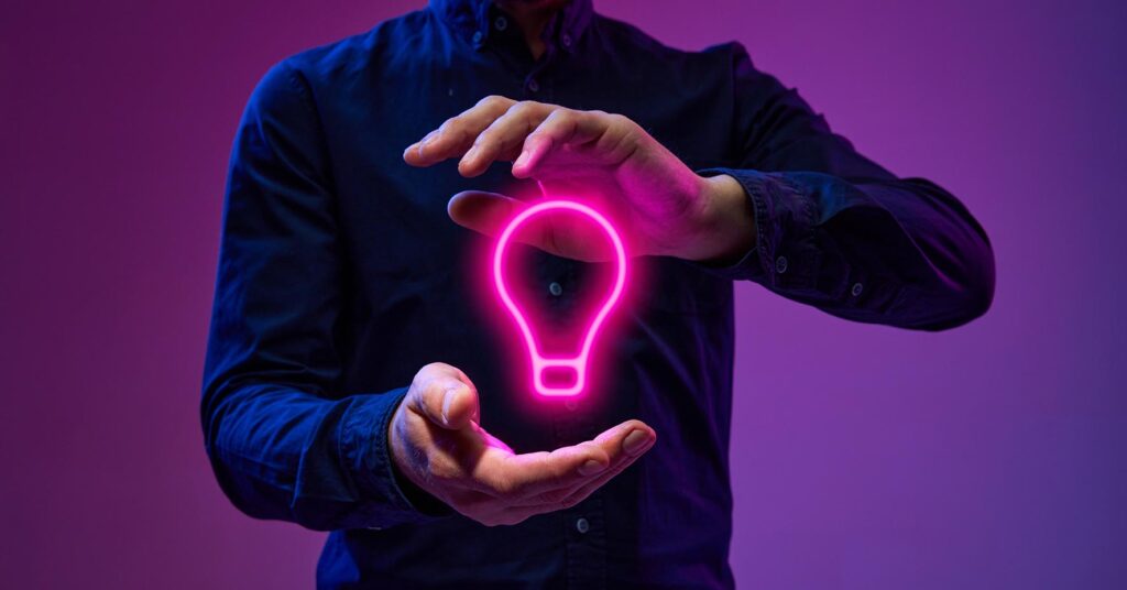 Man floating a pink neon lightbulb between his hand
