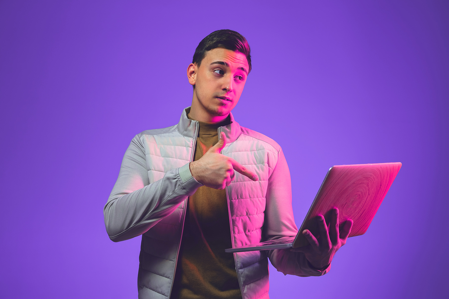 Man Pointing to Laptop With Purple Background