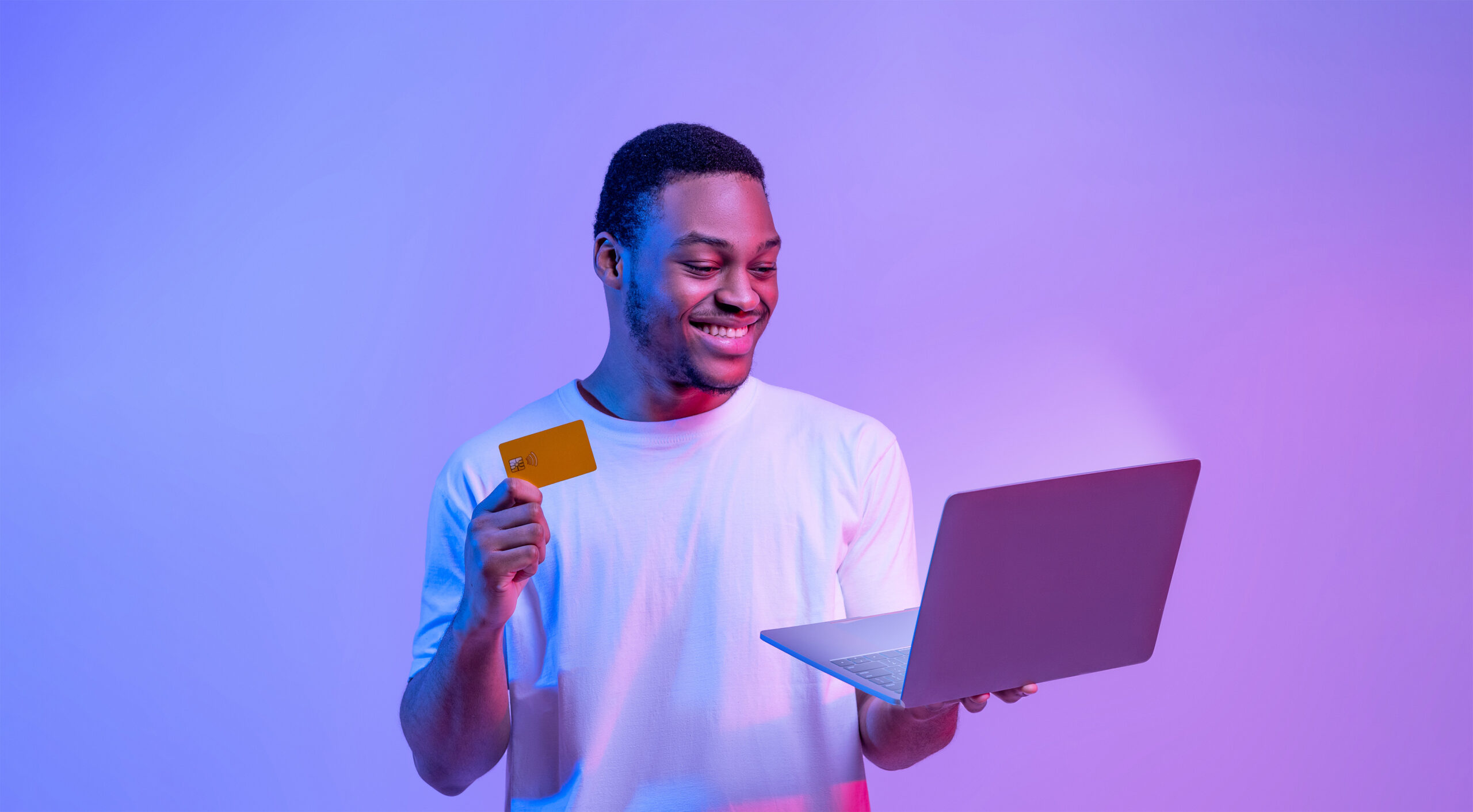 Man holding credit card smiling at laptop